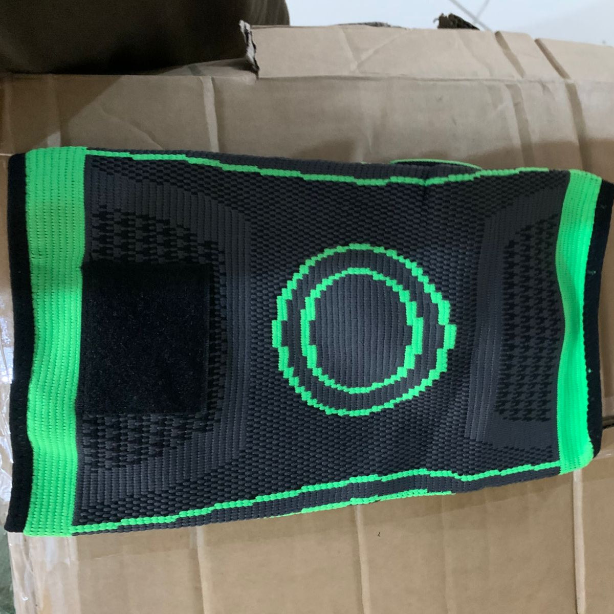 Black and green knee brace on a cardboard box