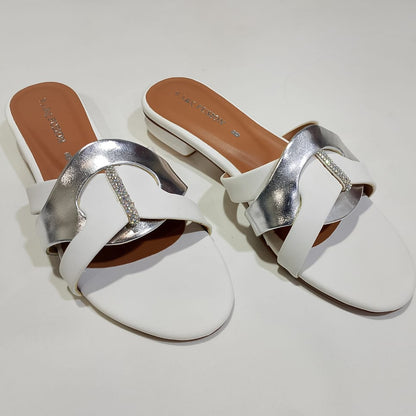 Pair of white sandals with silver straps on a light gray background